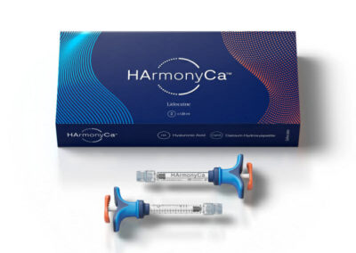 A blue and orange HAmonyCa box with white text is shown behind two syringes filled with clear liquid, each labeled HAmonyCa and featuring blue plungers with orange tabs.